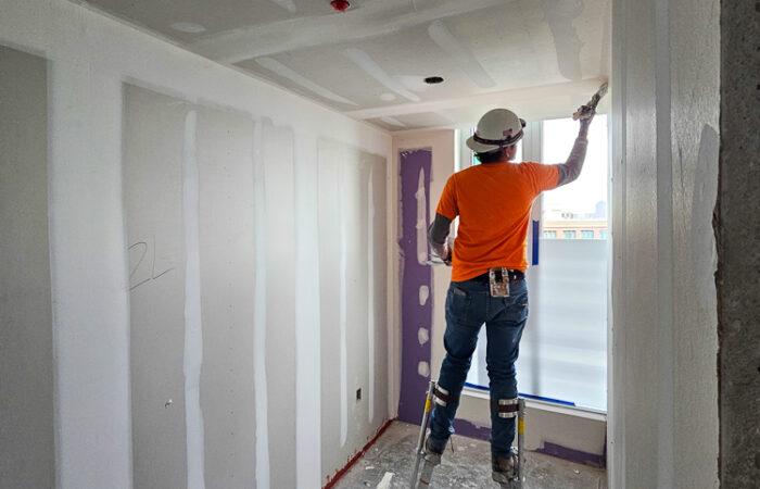 Robey Drywall employee fixing drywall at Allied Harbor Point building